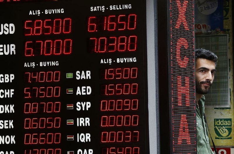 A shop owner stands next to a currency exchange Friday in Istanbul. Turkey’s lira fell once again as Turkey and the United States exchanged new threats of sanctions Friday.  
