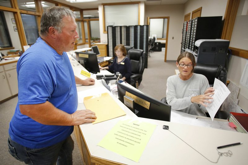 NWA Democrat-Gazette/DAVID GOTTSCHALK Marlena Young (right), deputy county clerk, reviews paperwork Friday with Duane Richert, Elkins' Ward 1 Position 2 councilman, at the Washington County Clerk and Probate office in the courthouse in Fayetteville. Friday was the last day for candidates to file for municipal office.