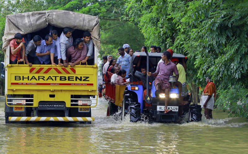 Flood affected people are rescued in a tractor, right as volunteers go for rescue work in a truck, left, at Kainakary in Alappuzha district, Kerala state, India, Friday, Aug. 17, 2018. Rescuers used helicopters and boats on Friday to evacuate thousands of people stranded on their rooftops following unprecedented flooding in the southern Indian state of Kerala that killed more than 320 people in the past nine days, officials said. (AP Photo/Tibin Augustine)