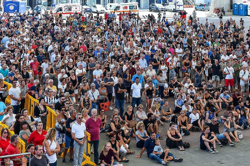 A crowd gathers Saturday outside the exhibition center in Genoa, Italy, where a giant screen showed the funeral service for some of the victims of last week’s bridge collapse.