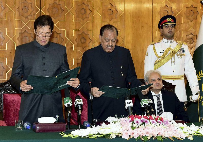 Pakistani President Mamnoon Hussain (center) administers the oath of office to new Prime Minister Imran Khan (left) on Saturday at the presidential palace in Islamabad in this photo released by Pakistan’s Press Information Department.