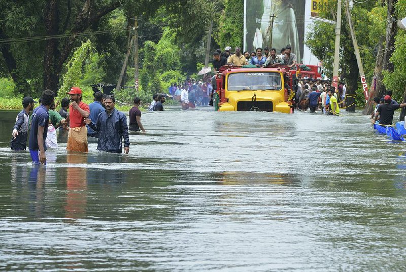 A truck takes people through a flooded road Saturday in Thrissur, India, in the southern state of Kerala.