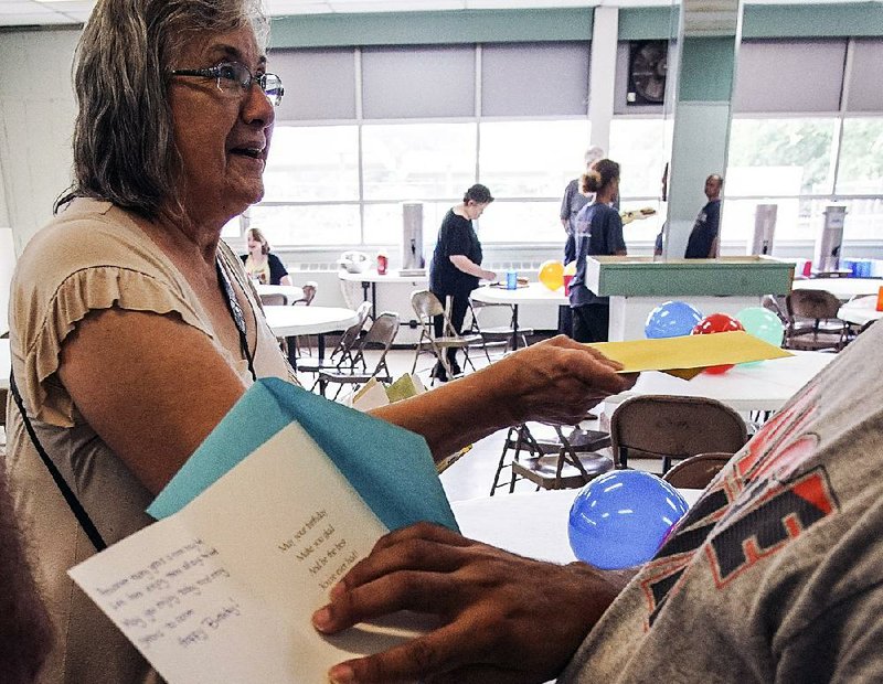 Rosemary Holloway with the Little Rock Compassion Center hands out birthday cards to people waiting in line for food Saturday during a party in their honor.  