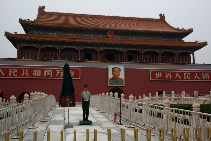 A member of the Chinese People's Liberation Army stands guard in front of a portrait of former Chinese leader Mao Zedong in Tiananmen Square in Beijing on July 28, 2016. =