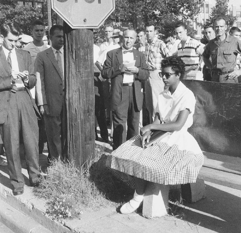 Arkansas Gazette reporter Jerry Dhonau (far left) is among journalists helping to shield Elizabeth Eckford from the angry crowd Sept. 4, 1957, as she waits for a bus during the Little Rock Central High Crisis.
