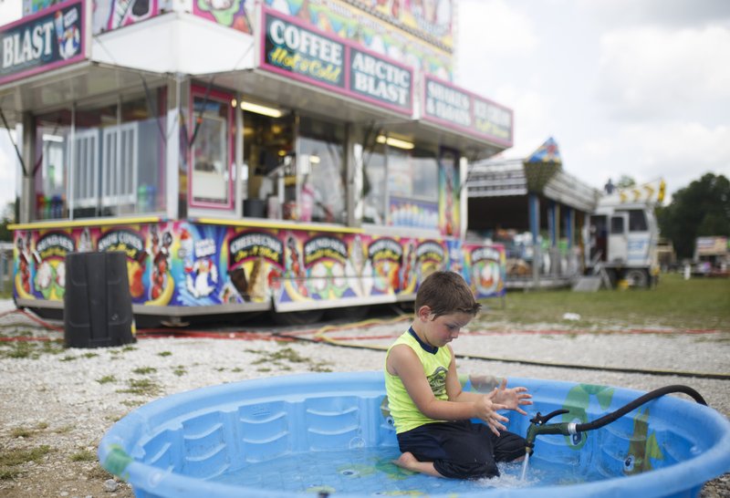 NWA Democrat-Gazette/CHARLIE KAIJO Elijah Watson, 6, of Morton, Miss. plays in a kiddie pool, Saturday at the Washington County fairgrounds in Fayetteville. The Washington County Fair kicks off Tuesday with 25 rides and attractions