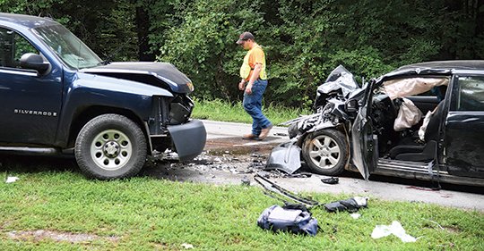 The Sentinel-Record/Grace Brown COLLISION SCENE: A volunteer with Piney Fire Department walks across the scene of a fatal collision between a Nissan Versa and a Chevrolet Silverado that occurred in the 600 block of Brady Mountain Road shortly after 5:30 p.m. Sunday.
