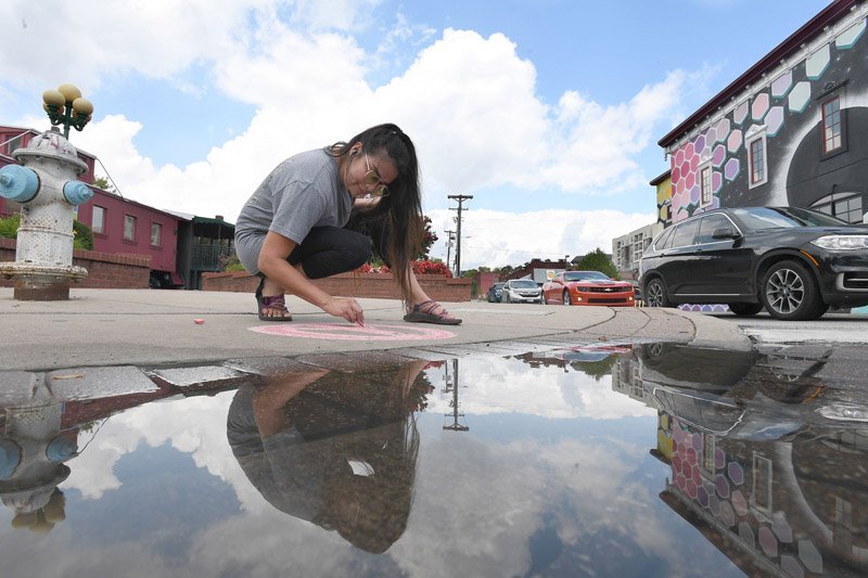 NWA Democrat-Gazette/J.T. WAMPLER Natalia Guerrero of Fayetteville uses chalk to make advertising Monday art for a Dickson Street pizzeria. Guerrero puts out fresh advertising after it rains and the water washes away the chalk.