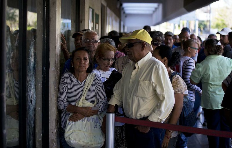 Customers wait to get new banknotes Tuesday at a government bank in Maracaibo, Venezuela. The country has devalued its currency 95 percent and taken other economic measures to confront hyperinflation. 