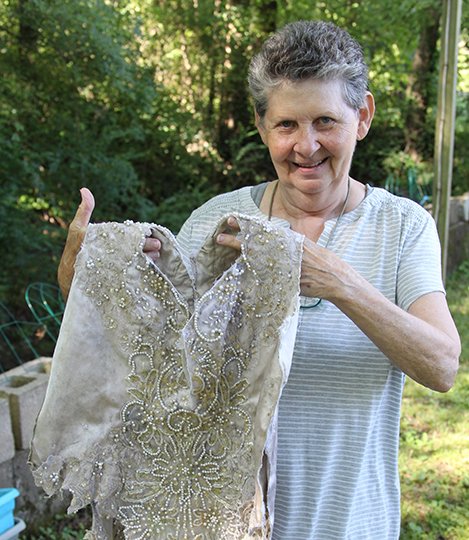 The Sentinel-Record/Richard Rasmussen WASHED UP: Linda Claiborne shows the bodice of a beaded wedding dress that washed up on the banks of Hot Springs Creek behind her home in late July.