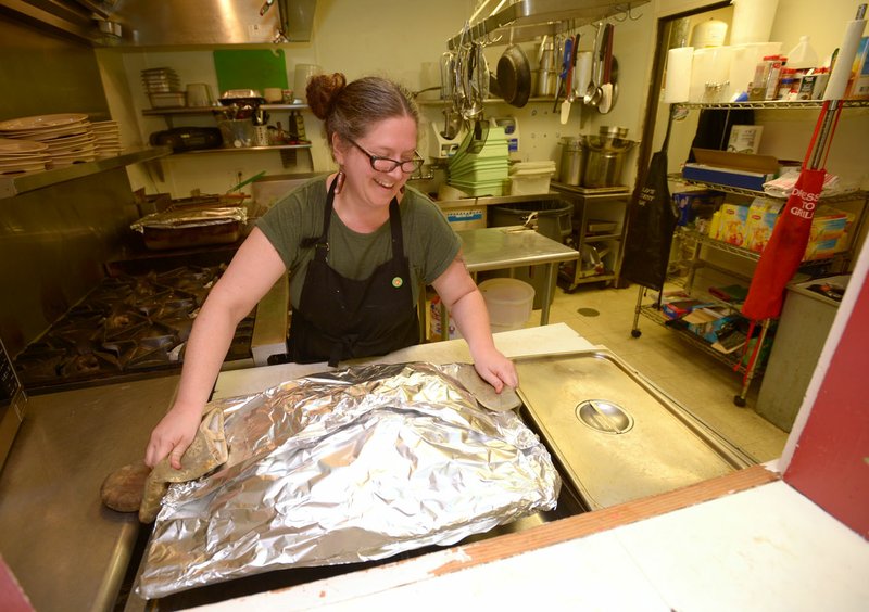 Rae Hall, housing monitor for the Salvation Army in Fayetteville, warms pizza donated by local Pizza Hut restaurants Friday, Aug. 17, 2018, at the Salvation Army's facility in Fayetteville. The shelter has expanded its overnight accommodations for people in need after the University of Arkansas decided to that camps on a nearby property had to leave by early September. About 40 people have taken advantage of the offer.