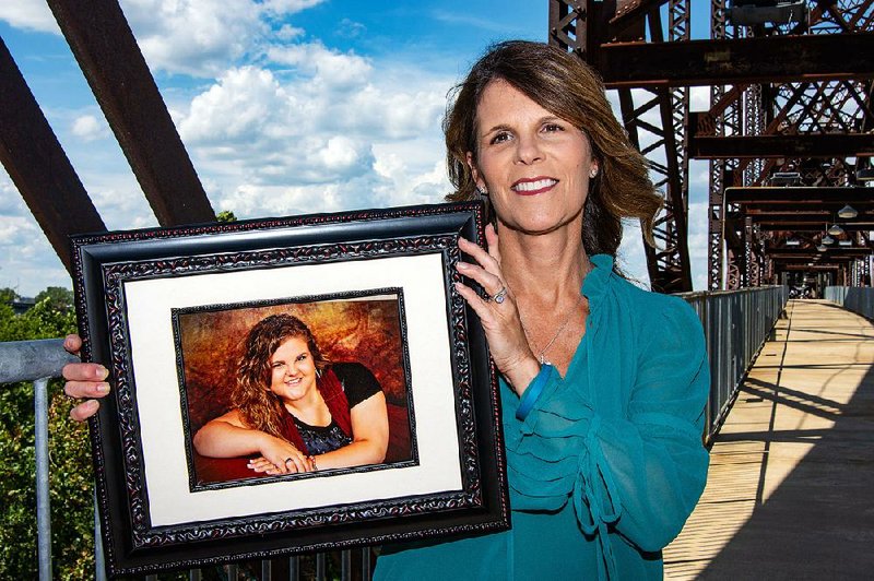 Sherri Fryar — with the Ovarian Cancer Coalition — stands on the bridge next to the Clinton Presidential Center, one of several bridges that will be illuminated with teal lights Sept. 7 on Teal Light Night. She is holding a photograph of her daughter, Taryn Claassen, who died of ovarian cancer in October.