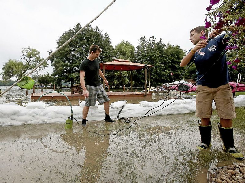 John Roberts (left) and Jake Bisbee tend water pumps Friday in the yard of a neighbor in Monona, Wis., as floodwaters threatened. Dane County, which includes the capital, Madison, received 11 inches of rain in the past week.  