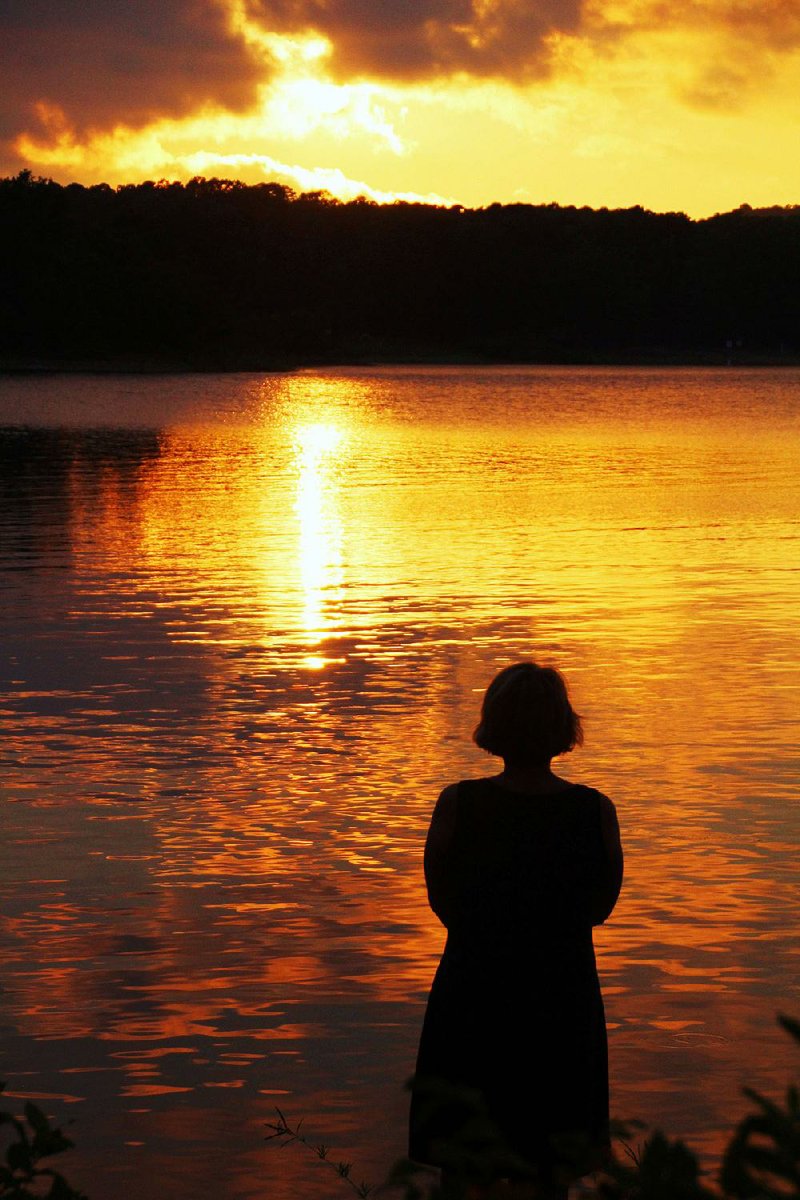 At the edge of an island in Lake Ouachita, camper Jill Skaggs enjoys a moment of Zen as the sun sets July 28.