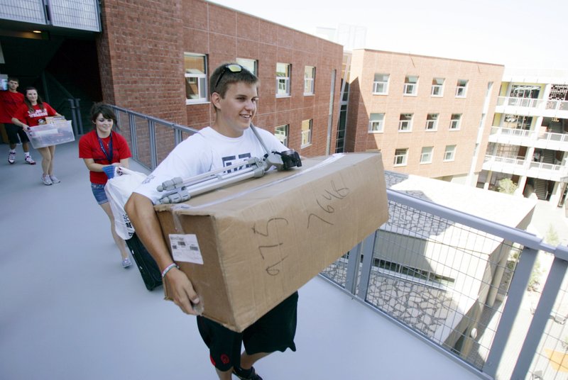 FILE - In this Aug. 17, 2011 file photo, Tony Lang carries a box while moving in to the new Likins Hall dorm at the University of Arizona in Tucson, Ariz. Moving to a new place can be taxing, emotionally and financially. Preparing a budget can help. Aside from the cost of hiring movers, consider less-obvious expenses like packing materials, furniture covers and storage. (Dean Knuth/Arizona Daily Star via AP)