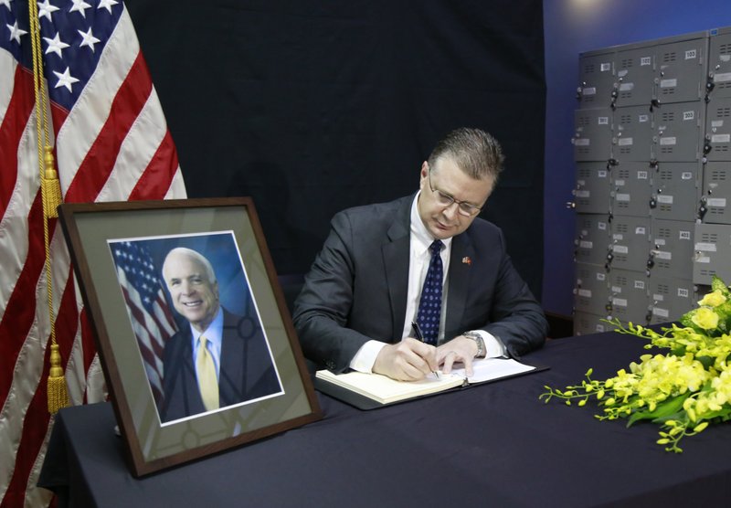 U.S. Ambassador to Vietnam Daniel Kritenbrink writes a note in a book of condolences for the late U.S. Senator John McCain in Hanoi, Vietnam, Monday, Aug. 27, 2018. Vietnam has been paying respect to McCain who died on Saturday. (AP Photo/Tran Van Minh)