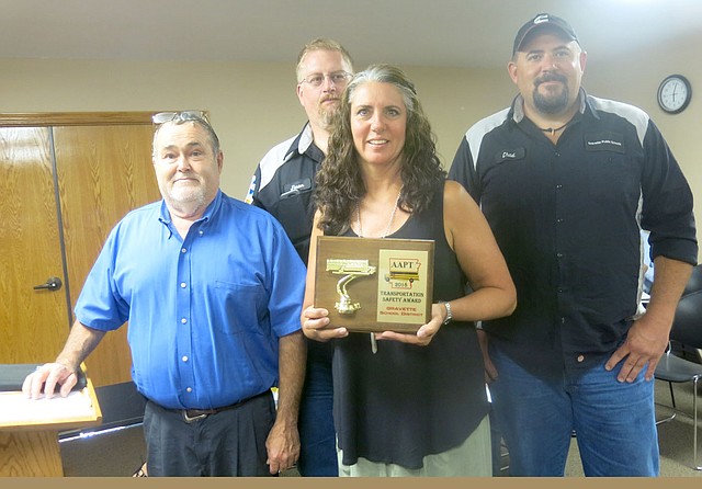 Westside Eagle Observer/SUSAN HOLLAND Richard Carver (left), Gravette public schools transportation and maintenance department supervisor, poses with his secretary, Melissa White, and bus technicians, Jason Curtis and Chad Whitehead, at the August meeting of the Gravette school board. White displays the 2018 Safest Fleet Award that Carver accepted for the department at the Arkansas Association of Pupil Transportation banquet in Hot Springs July 17. This is the second year the school bus fleet has earned the award.