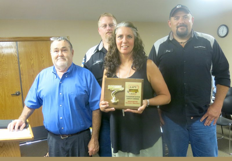 Westside Eagle Observer/SUSAN HOLLAND Richard Carver (left), Gravette public schools transportation and maintenance department supervisor, poses with his secretary, Melissa White, and bus technicians, Jason Curtis and Chad Whitehead, at the August meeting of the Gravette school board. White displays the 2018 Safest Fleet Award that Carver accepted for the department at the Arkansas Association of Pupil Transportation banquet in Hot Springs July 17. This is the second year the school bus fleet has earned the award.