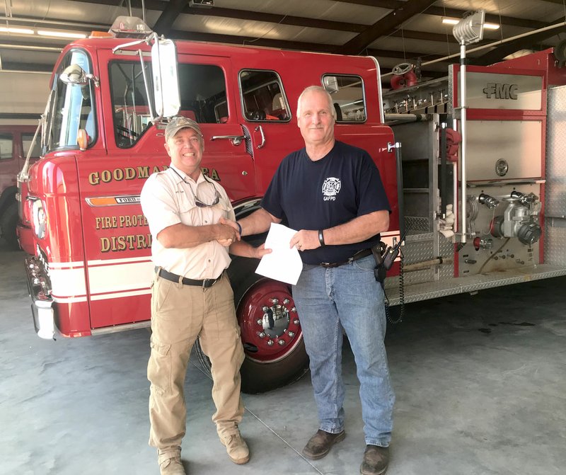 Photo by Sally Carroll/McDonald County Press Terry Cook, Forestry Crew Leader with the Missouri Department of Conservation (left) hands a grant check to Goodman Fire Chief Keith Estes. The grant is part of the Volunteer Fire Assistance Grant which is being distributed to rural fire departments in July and August. Approximately 174 fire departments are receiving checks for up to $4,000 to help with the purchase of gear and equipment to aid fire departments to suppress wildfires.