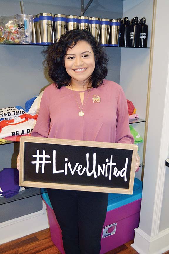 Joanna Grana-Maciel stands with promotional items for the United Way of Central Arkansas in its downtown office. Grana-Maciel, 23, is the new resource development director for the agency, and she will work with several programs, as well as help Hispanic clients.