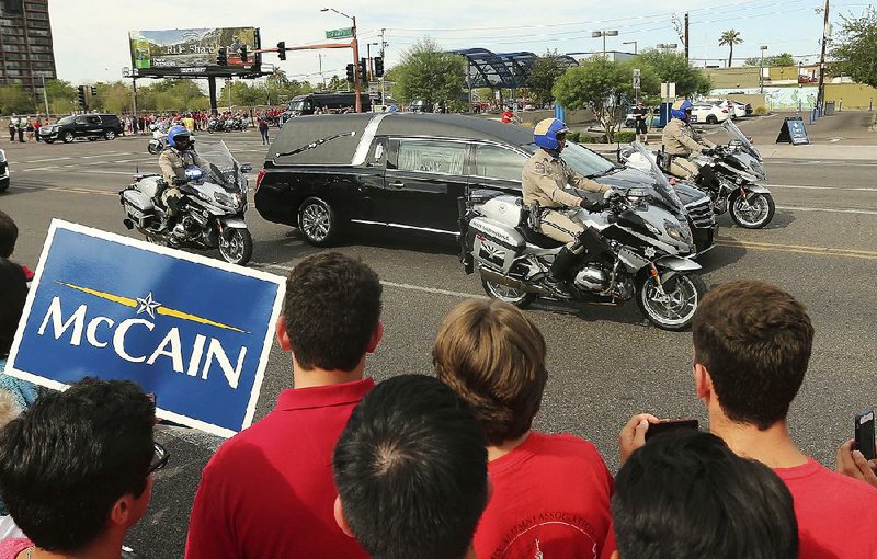 People line the street Thursday as a hearse carries John McCain’s body to a memorial service in Phoenix. Former Vice President Joe Biden headed the line-up of a half dozen speakers at the service. Today, McCain’s body is to lie in state in the U.S. Capitol rotunda.