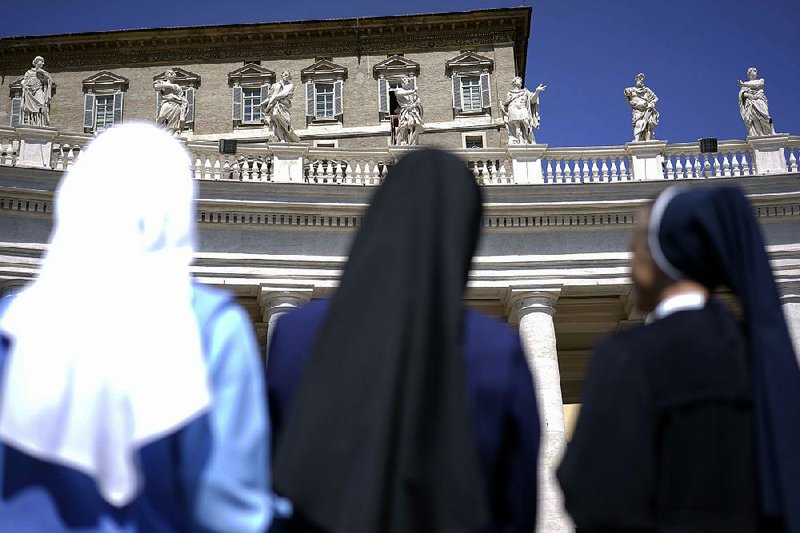 Nuns look up at Pope Francis delivering his blessing during the Regina Coeli prayer he celebrated from the window of his studio overlooking St. Peter’s Square in 2014, at the Vatican. 