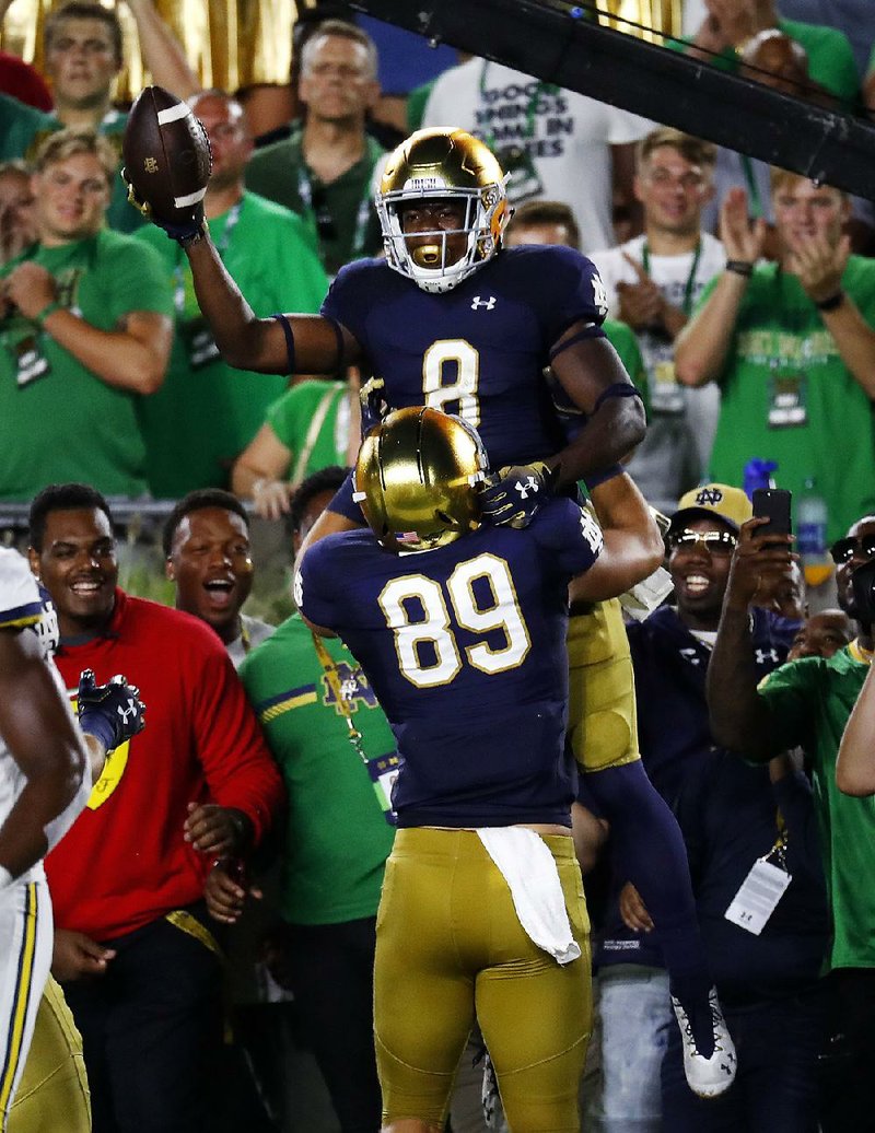 Notre Dame’s Jafar Armstrong (8) celebrates his 4-yard touch- down run with Brock Wright (89) during the first half of the No. 12 Fighting Irish’s 24-17 victory over No. 14 Michigan on Satur- day in South Bend, Ind.