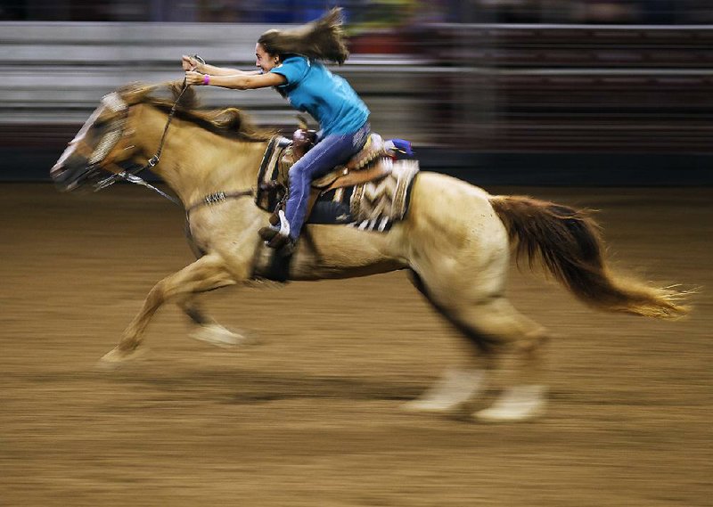 Harley Fleming races her horse across the arena in the Buckaroo Barrels Draw during Saturday events at the Arkansas State Cham- pionship Horse Show held in the Arkansas State Fairgrounds in Little Rock.