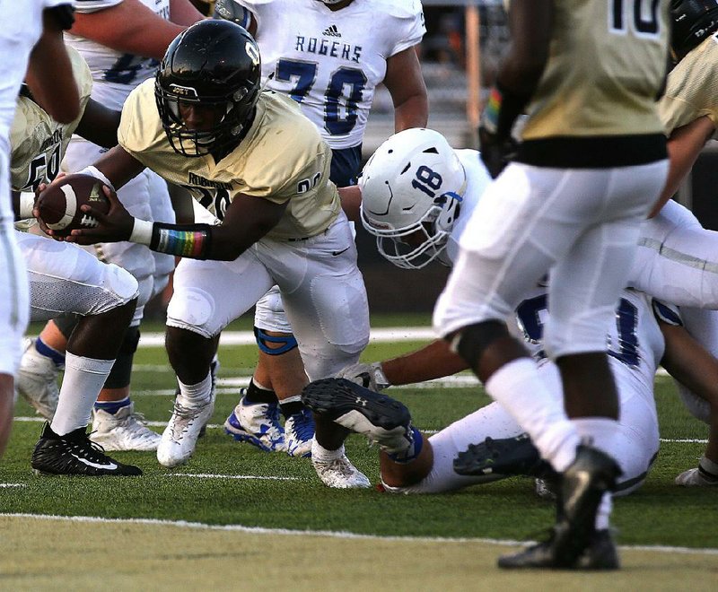 Joe T. Robinson running back Tyler Jones lunges the ball across the goal line as he is hit by Rogers linebacker Timothy Howard (18) during the first quarter of the Senators’ 35-14 victory over the Mounties on Friday night at Charlie George Stadium in Little Rock. More photos are available at arkansasonline.com/galleries.