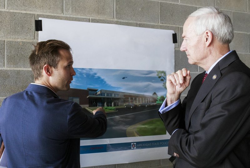 FILE — J.R. Davis and Gov. Asa Hutchinson, right, look at a picture of the Arkansas State Police headquarters in Lowell.