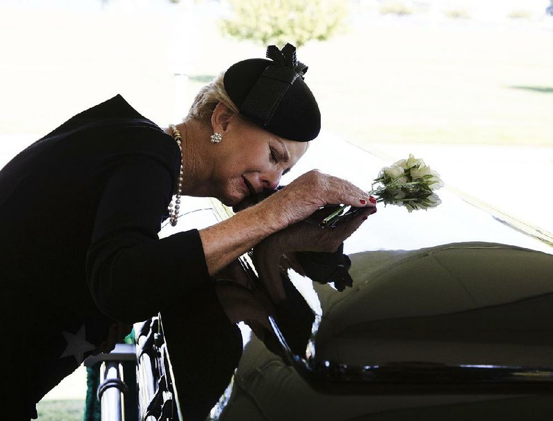Cindy McCain, the widow of Sen. John McCain, lays her head on his casket Sunday during a burial service in Annapolis, Md., in this photo provided by the McCain family. 