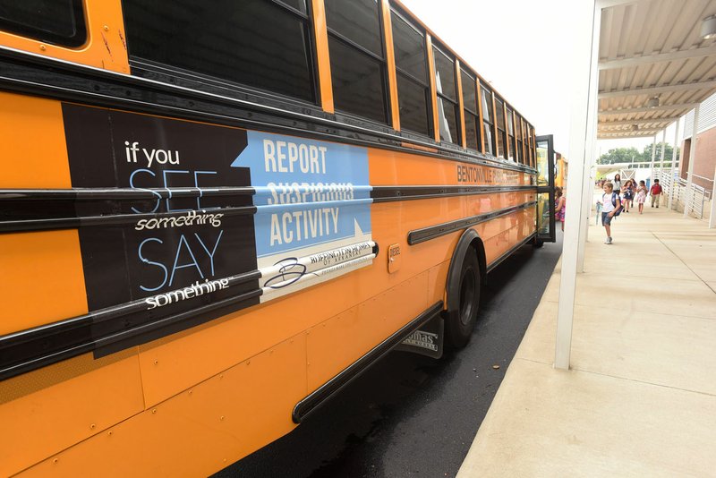 NWA Democrat-Gazette/FLIP PUTTHOFF A Bentonville school bus displays an "If you see something, say something," message Wednesday at Willowbrook Elementary School. The School Board approved putting signs on its buses in April, making Bentonville not only the largest, but also one of the first school districts in the state to do so.