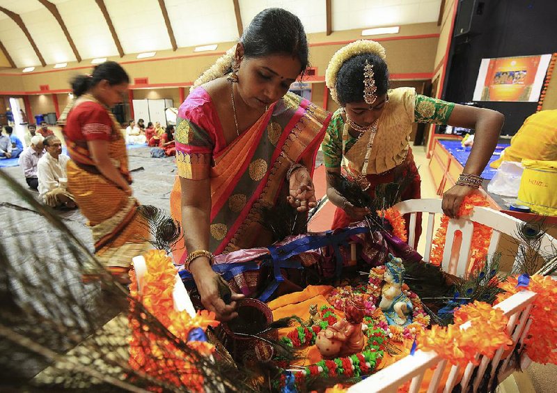 Viji Sridharan (left) and her daughter, Bhavna Sridharan, 12, prepare the cradle of Krishna on Monday in Little Rock during an event honoring the Hindu god. More photos are available at www.arkansasonline.com/galleries. 