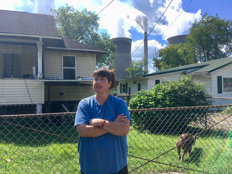 In this Aug. 23, 2018 photo, Andrea Maxey of Poca, W.Va., speaks outside her home with the American Electric Power&#x2019;s John Amos coal-fired power plant is in the background across the Kanawha River in Winfield. Maxey says emissions from the plant aren&#x2019;t a nuisance. President Donald Trump picked West Virginia where he announced rolling back pollution rules for coal-fired power plants. But he didn&#x2019;t mention that the northern two-thirds of West Virginia, with the neighboring part of Pennsylvania, would be hit hardest. (AP Photo/John Raby)