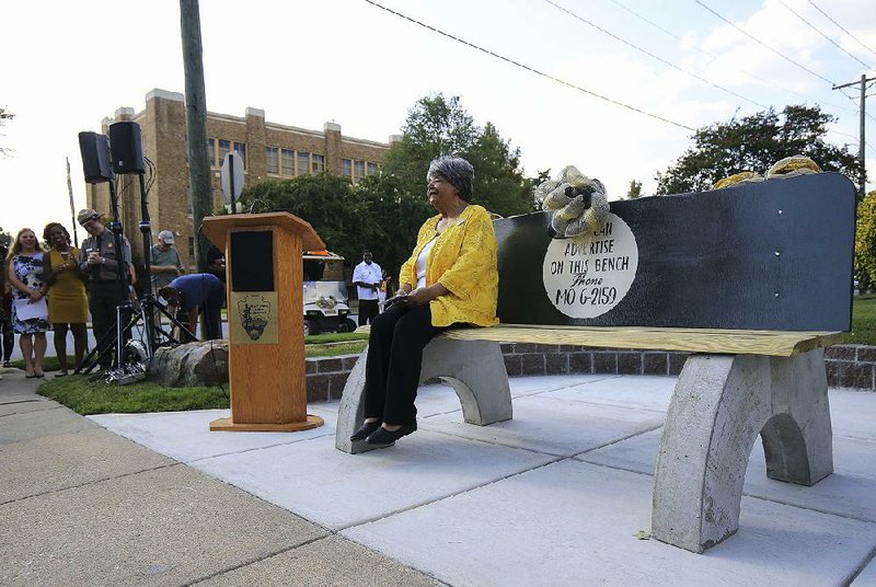 Elizabeth Eckford takes a seat Tuesday on a bench dedicated in her honor across from Little Rock Central High School. The bench is a replica of the public city bus bench where Eckford sat in 1957, surrounded by angry school desegregation protesters. 