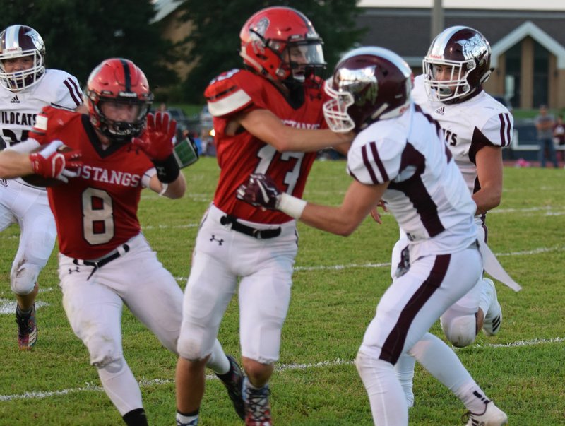 RICK PECK/SPECIAL TO MCDONALD COUNTY PRESS McDonald County wide receiver Reece Cooper (13) throws a downfield block for running back Oakley Roessler during the Mustangs' 21-13 win over Logan-Rogersville on Aug. 31 at MCHS.