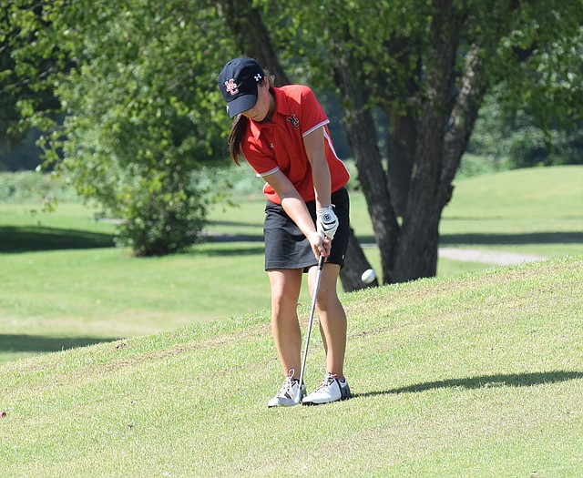 RICK PECK/SPECIAL TO MCDONALD COUNTY PRESS McDonald County's Lily Allman hits a chip shot on the first hole at Elk River Golf Course in Noel during a match with Gravette High School. The Lady Lions claimed a 147-156 win over the Lady Mustangs.