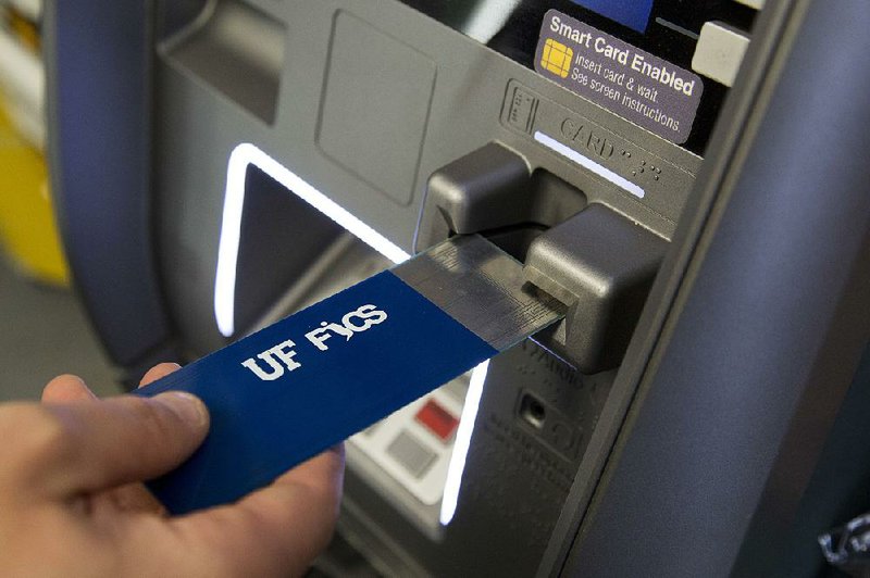 In this April 18 photo, a detective with the New York City Police Department uses a detection device that indicates if a credit card skimmer is in use at an ATM machine at a New York convenience store. The device is under development by the Florida Institute for Cybersecurity Research. 