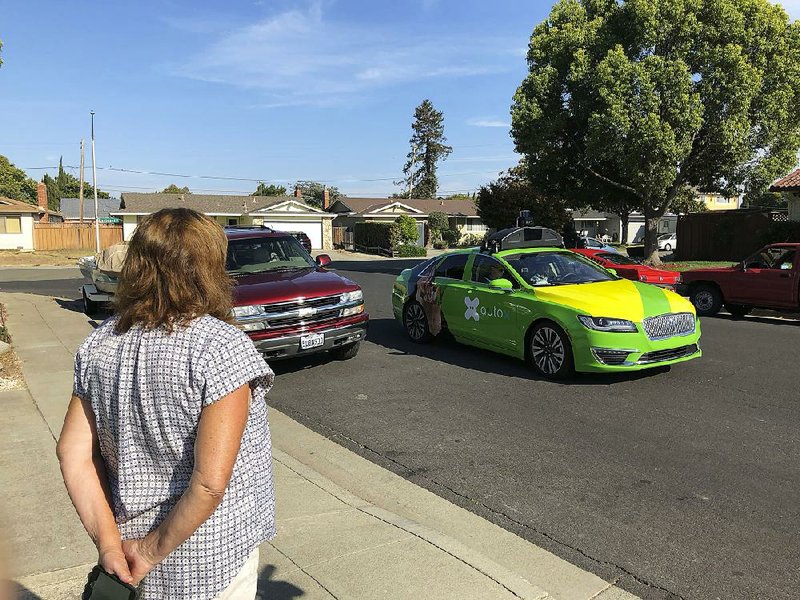 Customer Maureen Blaskovich waits last month for groceries delivered by a self-driving vehicle outfitted with technology by AutoX in San Jose, Calif.  
