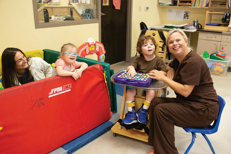 Physical therapist Melinda Grimes, from left, Abigail Rivera, Braxton Maxwell and occupational therapist Tina Osburn work on some skills at Building Bridges. The center’s Fine Arts for Exceptional Hearts fundraiser is coming up Sept. 27 at the Veterans Park Event Center in Cabot is vital to the organization’s operation.