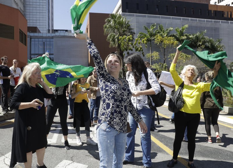 Supporters of Brazilian presidential candidate Jair Bolsonaro, who was stabbed during a campaign event, wave national flags as they gather outside the Albert Einstein Hospital, where the candidate was transferred, in Sao Paulo, Brazil, Friday, Sept. 7, 2018. Surgeon Luis Borsato said Bolsonaro was in serious but stable condition and would remain in intensive care for at least seven days. (AP Photo/Andre Penner)