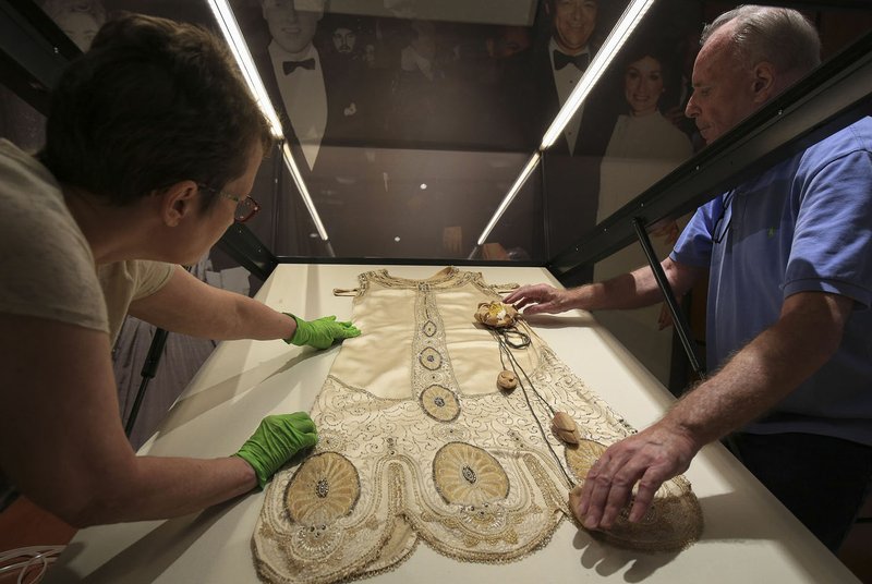 File Photo/STATON BREIDENTHAL Curator Jo Maack (left) and conservator Harold Mailand with Textile Conservation Services work placing the gown of First Lady Eula Terral in a case in preparation for the opening of "First Ladies of Arkansas: Women of Their Times" exhibit. The exhibit opens Sept. 14.