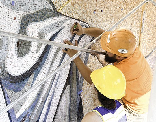 The Sentinel-Record/Grace Brown JESUS MOSAIC: Erin Holliday, left, and Vance Henson work to restore a large mosaic of Jesus Christ featured on the side of First United Methodist Church on Wednesday.