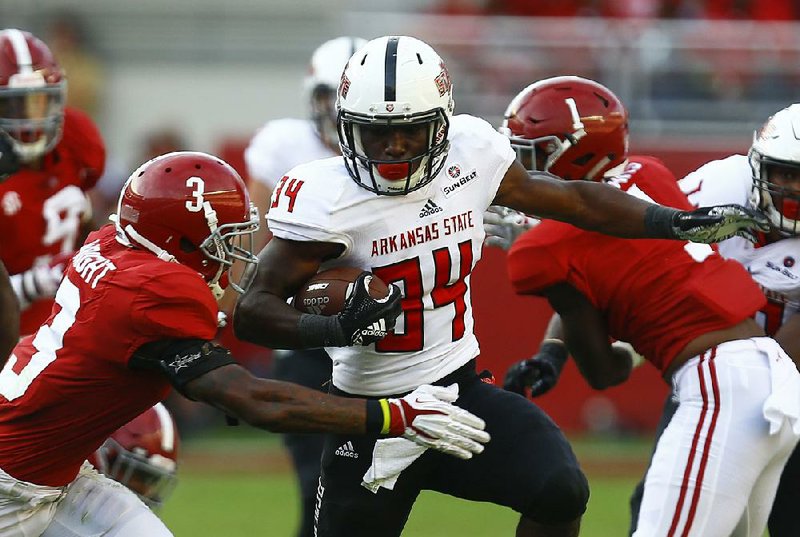 Arkansas State running back Marcel Murray (34) tries to get past Alabama defensive back Daniel Wright (3) as he carries the ball Saturday during the second half of the Red Wolves’ 57-7 loss to the top-ranked Crimson Tide in Tuscaloosa, Ala. Murray had seven carries for 34 yards.   