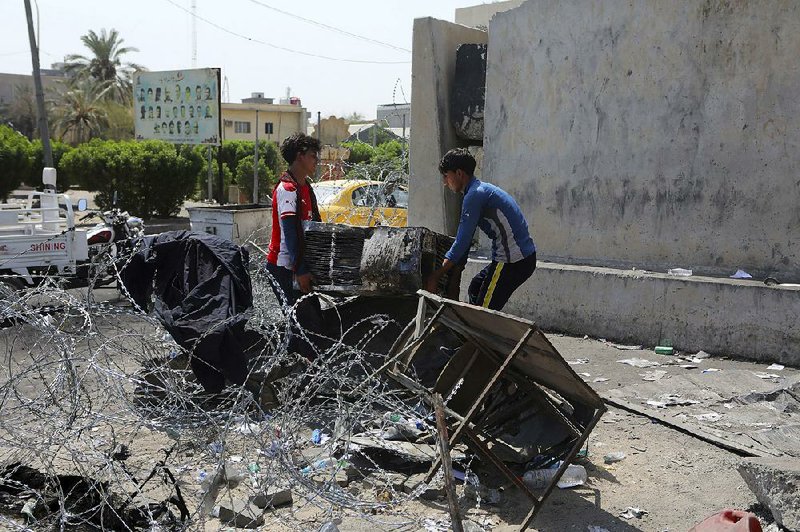 Workers remove damaged furniture Saturday from a burned government building in Basra, Iraq.  