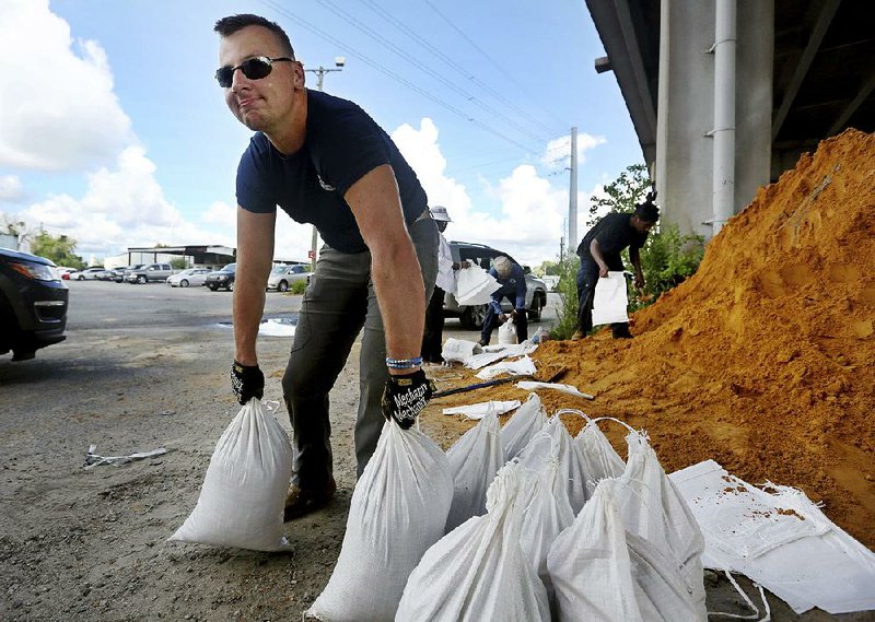 Kevin Orth loads sandbags into cars on Milford Street as he helps residents prepare for Hurricane Florence on Monday in Charles- ton, S.C.