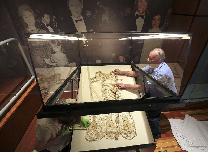 Curator Jo Ellen Maack (left) and conservator Harold Mailand with Textile Conservation Services work at the Old Statehouse Museum placing the gown of first lady Eula Terral in preparation for the unveiling of “First Ladies of Arkansas: Women of Their Times.”