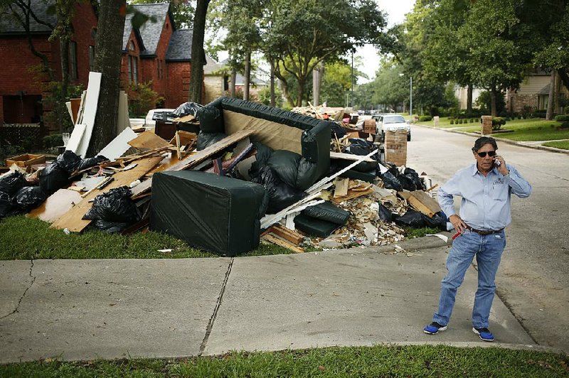 Construction company owner Frank Jones talks on a cellphone next to debris from a house in Spring, Texas, that was flooded after Hurricane Harvey in September 2017. A bill to overhaul the Federal Emergency Management Agency’s flood insurance program has been stalled in Congress since November. 