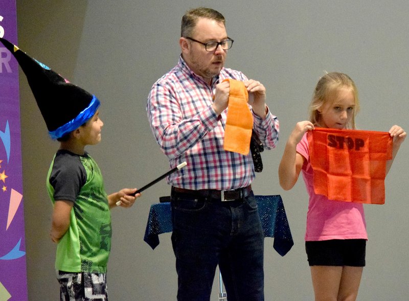 Westside Eagle Observer/MIKE ECKELS Scott Davis puts a pair of handkerchiefs together with the help of assistant Brooklyn Thompson (right) and apprentice Anthony Sanchez (left) during the "Making Accidents Disappear" magic show at Northside Elementary School in Decatur Aug. 30. Davis talked to the Northside students about electrical safety.
