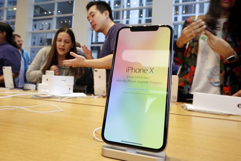In this Nov. 3, 2017, file photo, customers buy the iPhone X at the Apple Store on New York's Fifth Avenue. (AP Photo/Richard Drew, File)